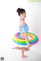 A young girl in a blue and white bathing suit holding a rainbow ring.