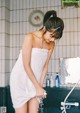 A woman in a white towel standing in a bathroom.