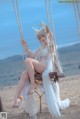 A woman sitting on a swing on the beach.