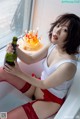 A woman sitting in a bathtub holding a bottle of beer.