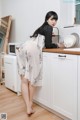 A woman standing in a kitchen next to a microwave.