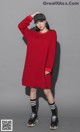 a woman in a red dress and black hat posing for a picture