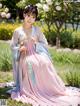 A woman in a pink and blue dress sitting in the grass.