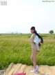 A naked woman standing in a field of tall grass.