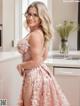 A woman in a pink dress standing in a kitchen.