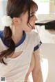 A woman in a white shirt is drinking water from a faucet.