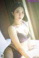 A woman in a purple lingerie sitting on a bed.