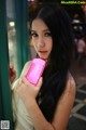A woman holding a pink cell phone in her hand.